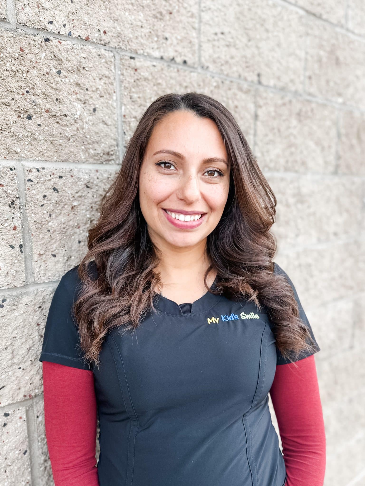 Smiling person outdoors near brick wall