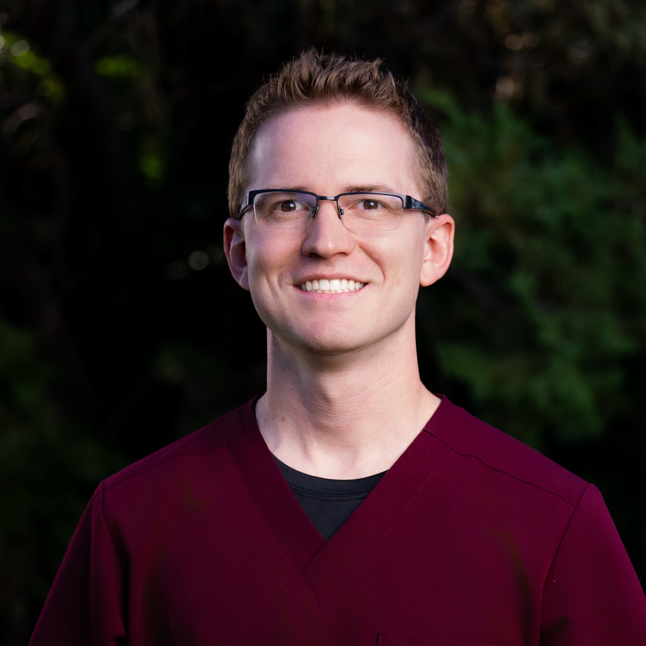Smiling person wearing glasses and maroon shirt